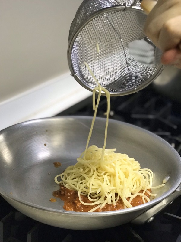 フライパンで湯煎したパスタソースと茹でた生パスタを和えているところ