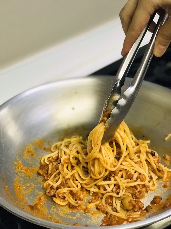 フライパンで湯煎したパスタソースと茹でた生パスタを和えているところ